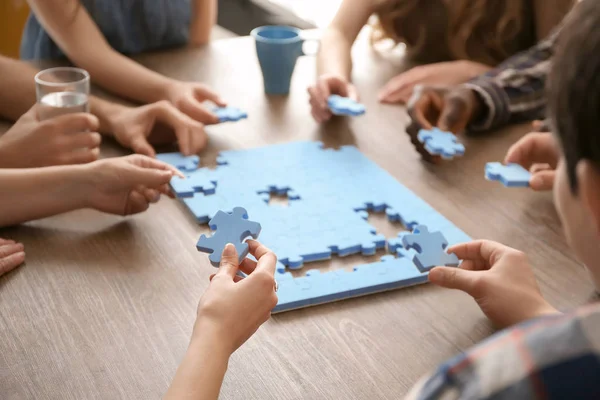 People with puzzle at table, closeup of hands. Unity concept