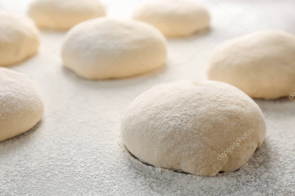 Fresh raw dough with flour on table
