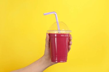 Güler yüzlü lezzetli renk arka plan üzerinde ile plastik bardak tutan kadın