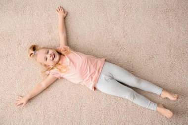 Sevimli küçük kız rahat halı üzerinde evde, üstten görünüm yalan