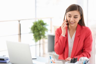 İş yerinde telefonla konuşan genç bir kadın.