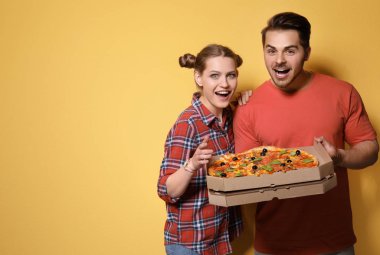 Renk arka plan üzerinde lezzetli pizza ile çekici genç Çift
