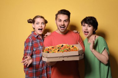 Renk arka plan üzerinde lezzetli pizza ile arkadaş grubu