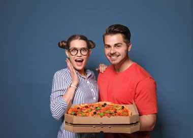 Renk arka plan üzerinde lezzetli pizza ile çekici genç Çift