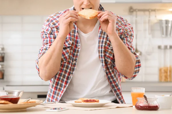Νεαρός Άνδρας Νόστιμο Φρυγανισμένο Ψωμί Τρώει Στο Τραπέζι Στην Κουζίνα — Φωτογραφία Αρχείου