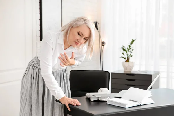 Mature woman having heart attack at workplace
