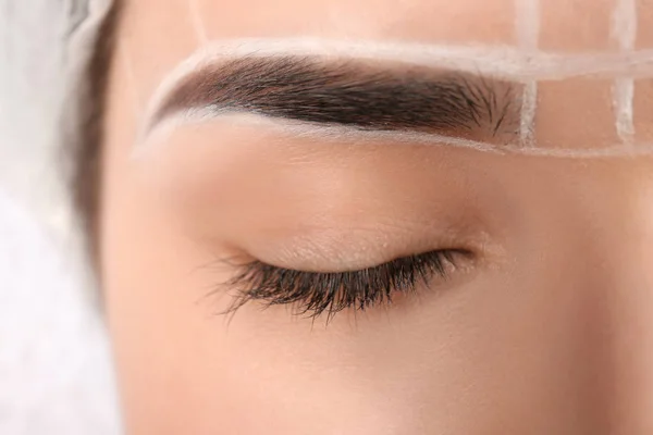 Young woman with marks on face before eyebrow permanent makeup procedure, closeup