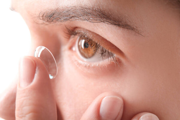 Young woman putting contact lens in her eye, closeup