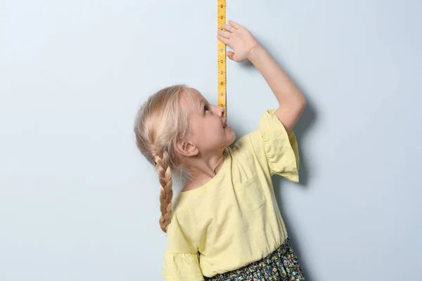 Маленькая Девочка Измеряет Свой Рост Светлом Фоне — стоковое фото