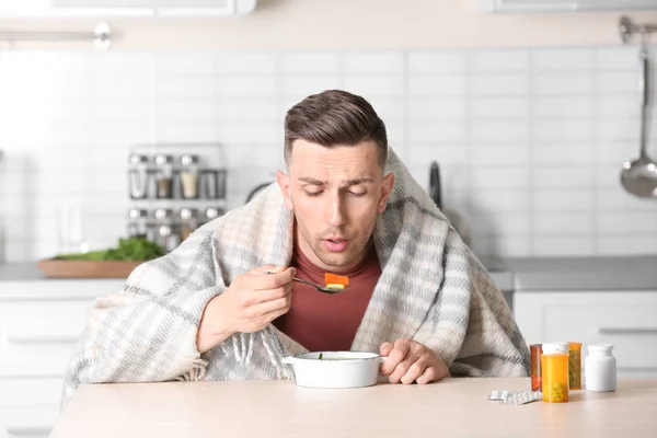 生病的年轻人吃肉汤在厨房餐桌上治疗感冒 — 图库照片