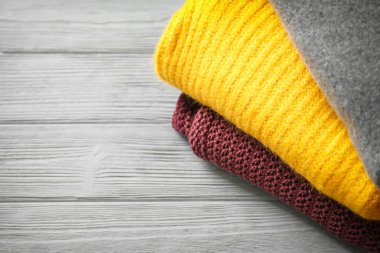 Ahşap masa üzerinde sıcak örme giysiler yığını