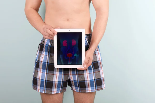 Молодой Человек Держит Таблетку Мочевой Системой Экране Цветном Фоне — стоковое фото