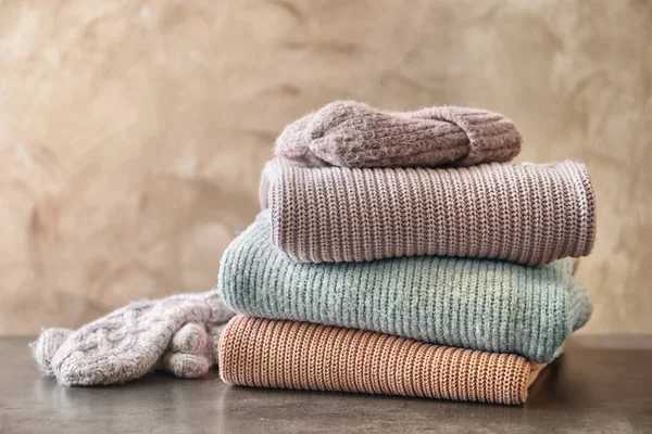 Stack of warm knitted clothes on table