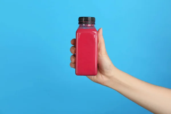 Frau Hält Flasche Mit Leckerem Smoothie Auf Farbigem Hintergrund — Stockfoto