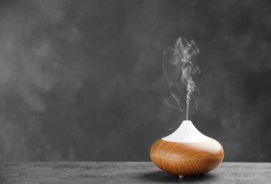 Aroma Yağı difüzör tabloda gri bir arka plana dayanır. Oda spreyi