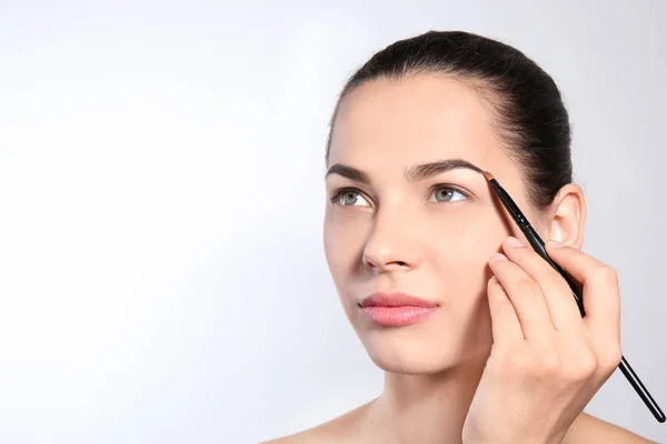 Young Woman Correcting Shape Eyebrow Brush Light Background — Stock Photo, Image