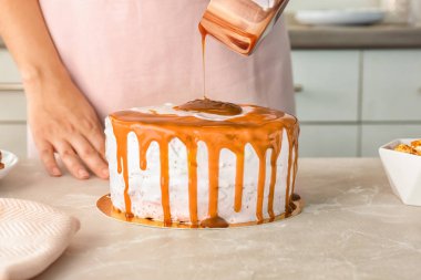 Genç kadın masada lezzetli ev yapımı kek üzerine karamel sos uygulama
