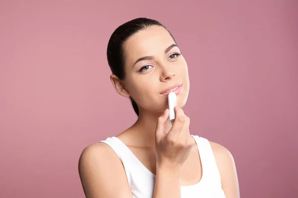 Młoda Kobieta Stosując Balsam Jej Usta Przed Kolor Tła — Zdjęcie stockowe