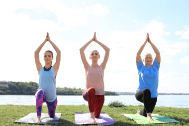 Kadınlar pratik yoga Nehri yakınında güneşli günde gurup