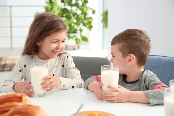 かわいい小さな子供たちのテーブルで牛乳で朝食を済ませ — ストック写真