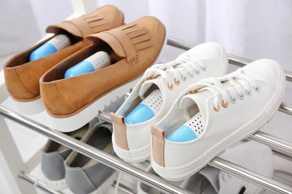 Shoes with capsule fresheners on rack in room