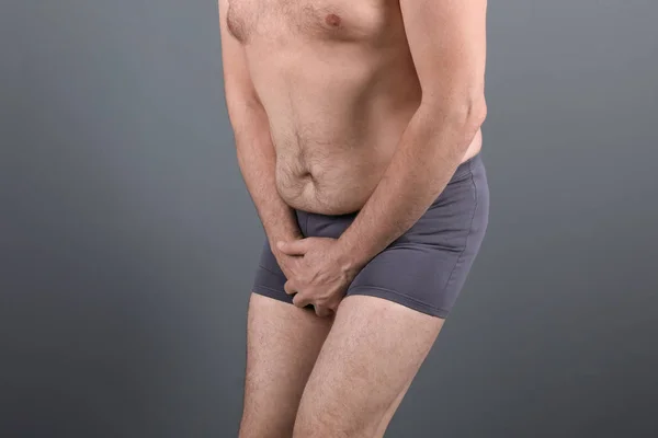 灰色の背景の痛みから苦しんでいる泌尿器科の問題と中年の男性 — ストック写真