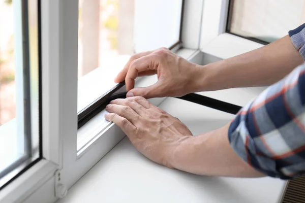 Joven Poniendo Cinta Espuma Sellado Ventana Interior — Foto de Stock