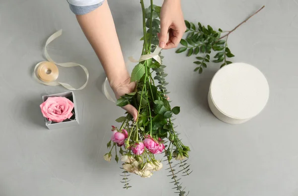 Female florist making beautiful bouquet at table, top view