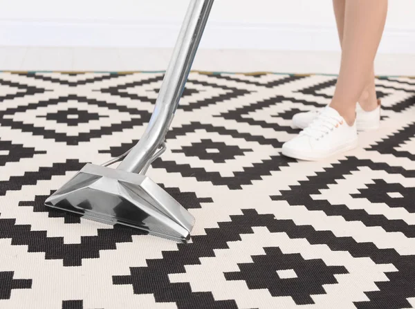 Female worker removing dirt from carpet with professional vacuum cleaner indoors
