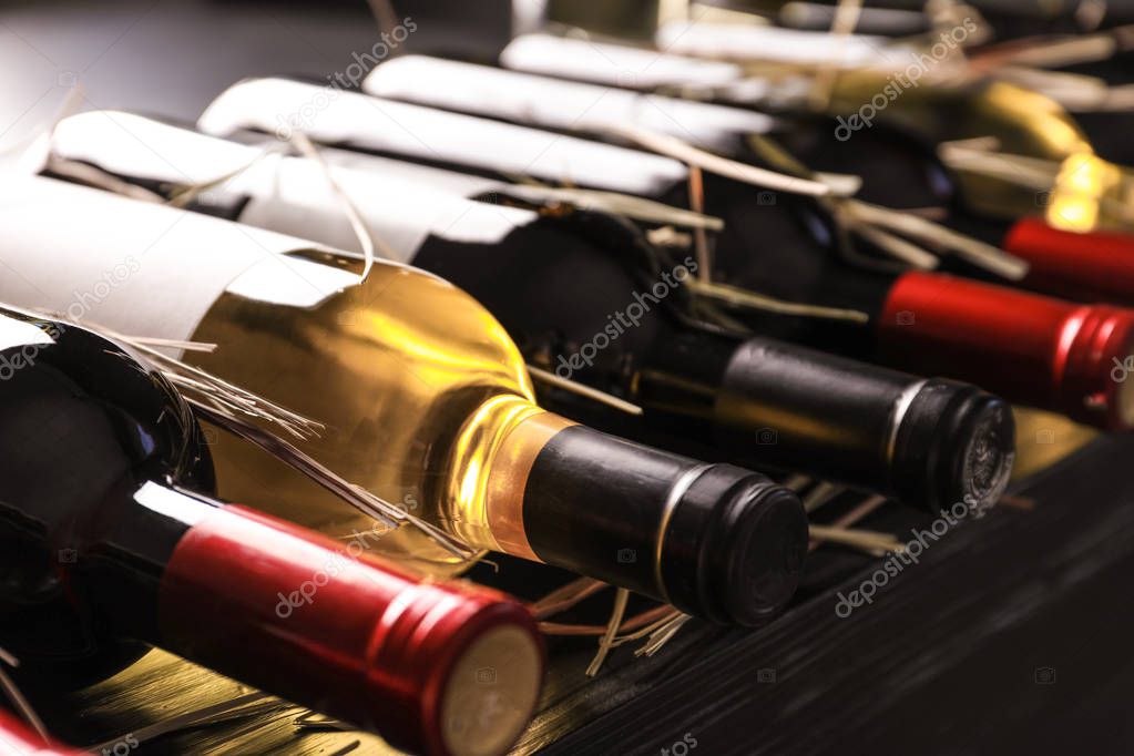 Bottles with delicious wine on shelf, closeup. Professional sommelier