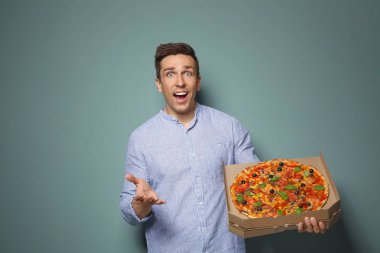 Renk arka plan üzerinde lezzetli pizza ile çekici bir genç adam