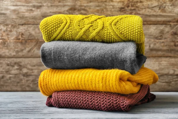 Stack of warm knitted clothes on table