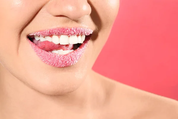 Beautiful young model with sugar lips on color background