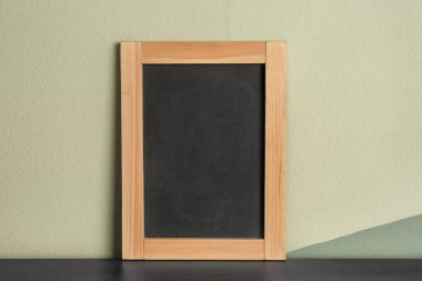 Küçük temiz kara tahta masa renk duvarının yakınında