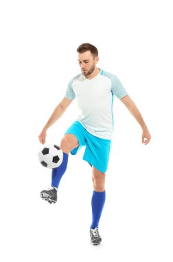 Genç adam beyaz arka planda futbol oynuyor.