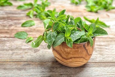 Bowl with fresh mint on wooden table clipart