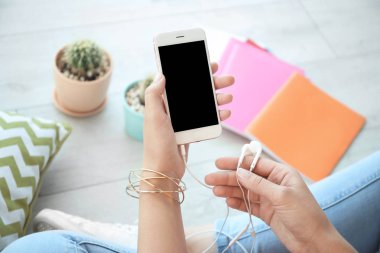 Boş ekran ve kulaklık ile cep telefonu elinde kapalı tutan genç kadın
