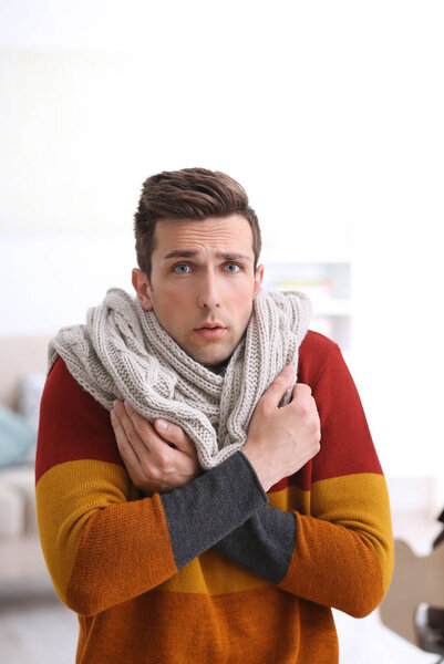 Sad young man suffering from cold on blurred background