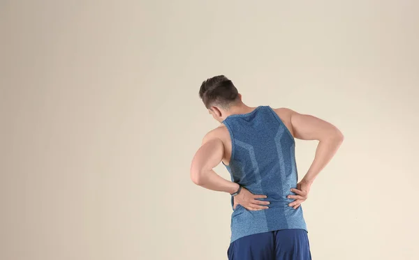 Mann Sportkleidung Leidet Rückenschmerzen Vor Hellem Hintergrund — Stockfoto