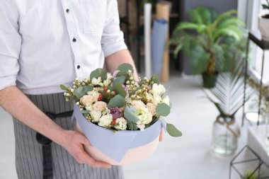 Erkek çiçekçi çiçek kutusuyla işyerinde holding