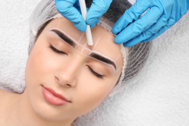 Genç kadın kaş kalıcı makyaj yordamı için closeup hazırlanıyor güzellik uzmanı