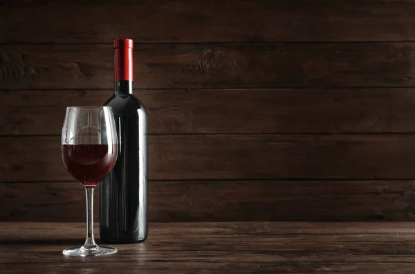 Glas Och Flaska Med Utsökt Rödvin Bordet Mot Mörk Bakgrund — Stockfoto