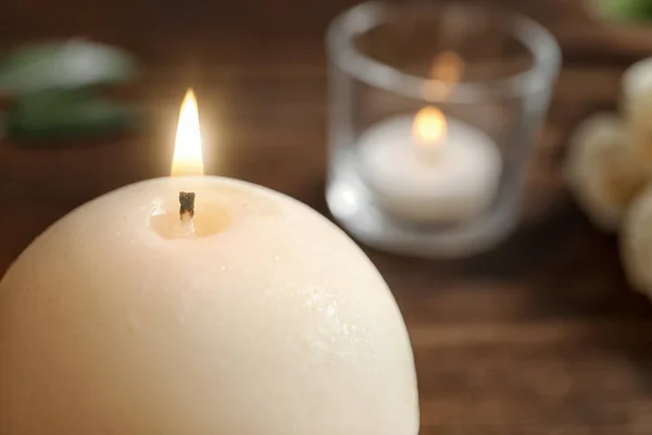 Round wax candle burning on table, closeup