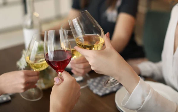 Young people with glasses of delicious wine at table