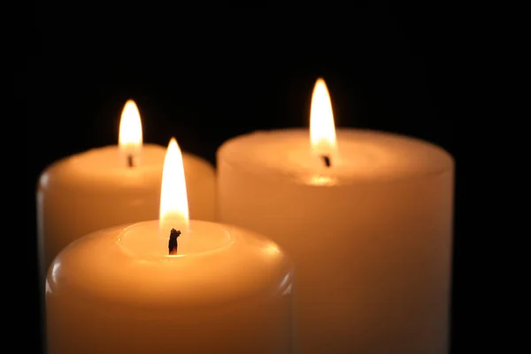 Wax candles burning on black background, closeup
