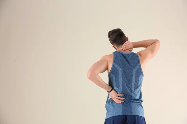 Mann Sportkleidung Leidet Rückenschmerzen Vor Hellem Hintergrund — Stockfoto