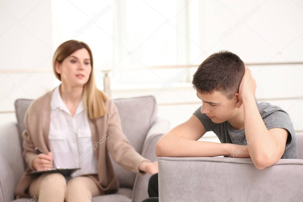 Young female psychologist working with teenage boy in office