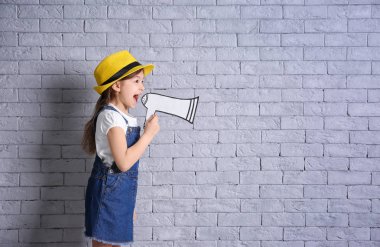 Tuğla duvar arka plan üzerinde kağıt megafon ile sevimli küçük kız