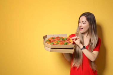 Lezzetli pizza renk arka plan üzerinde çekici genç kadın
