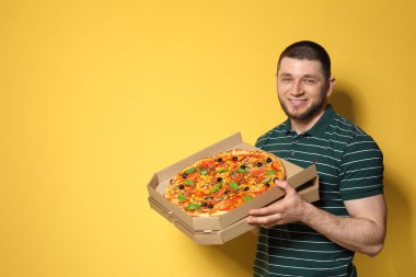 Renk arka plan üzerinde lezzetli pizza ile çekici bir genç adam